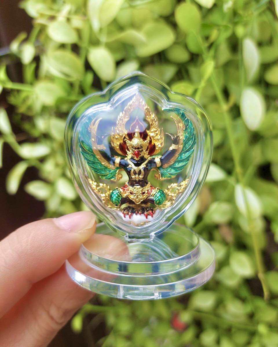 Thai Garuda car display amulet in clear heart shaped acrylic case on round stand held in hand