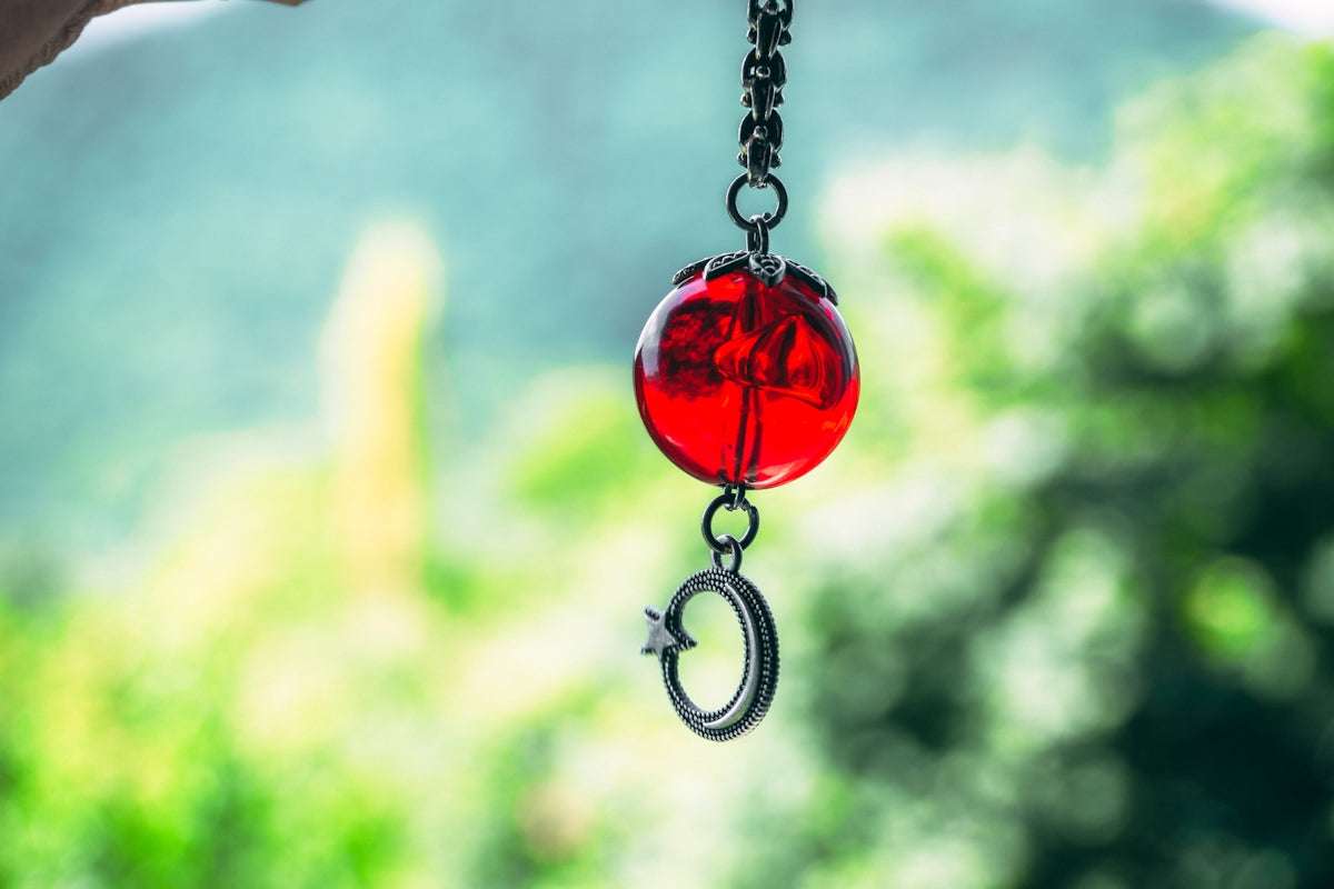 A red glass bead with a silver crescent moon charm.