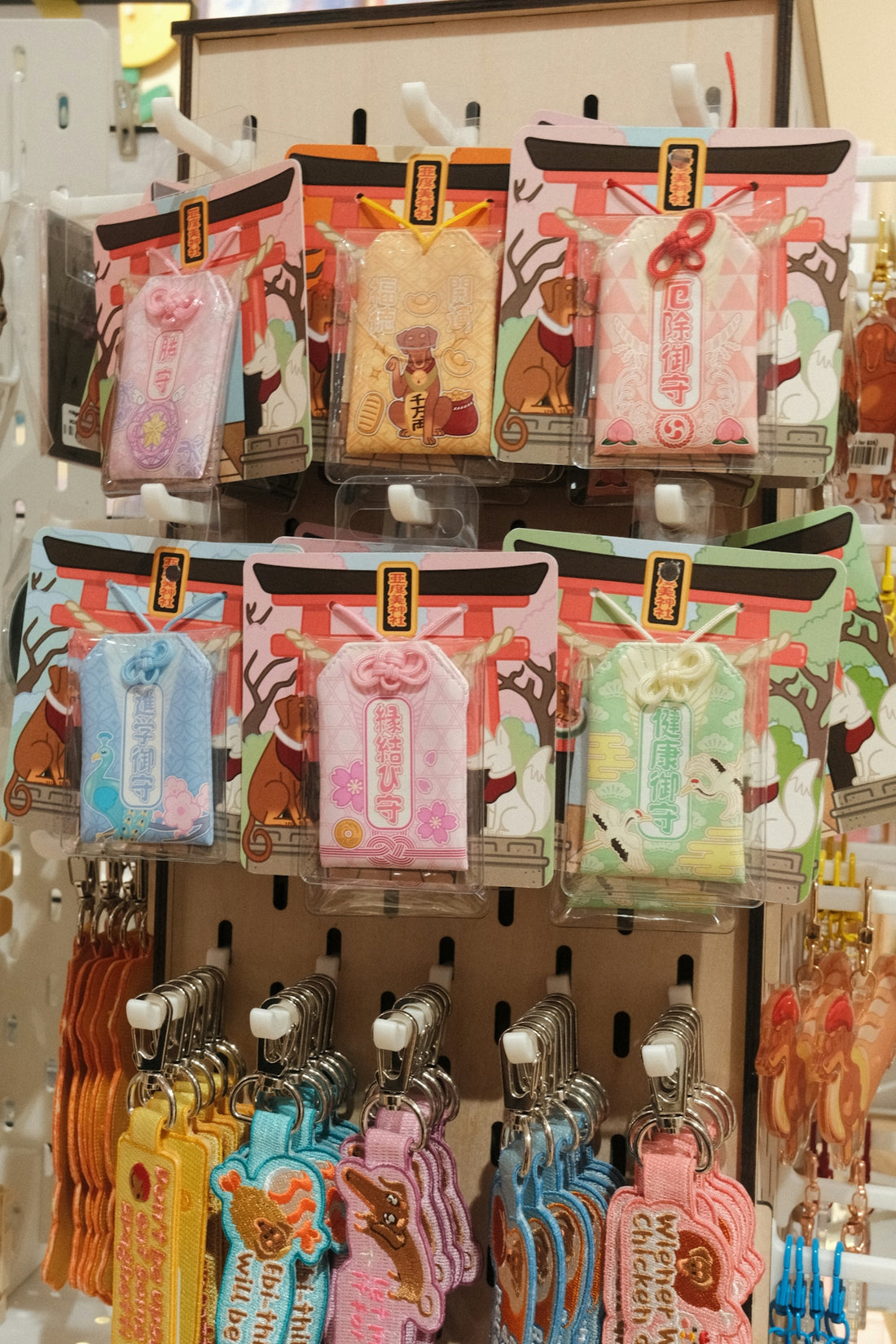 Colorful omamori charms and keychains displayed on a rack.