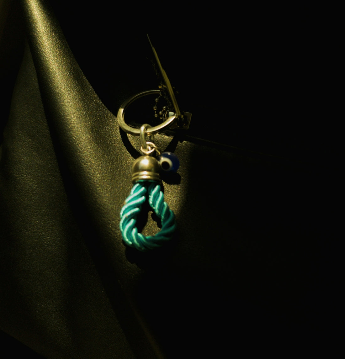A keychain with a turquoise rope noose and blue bead.