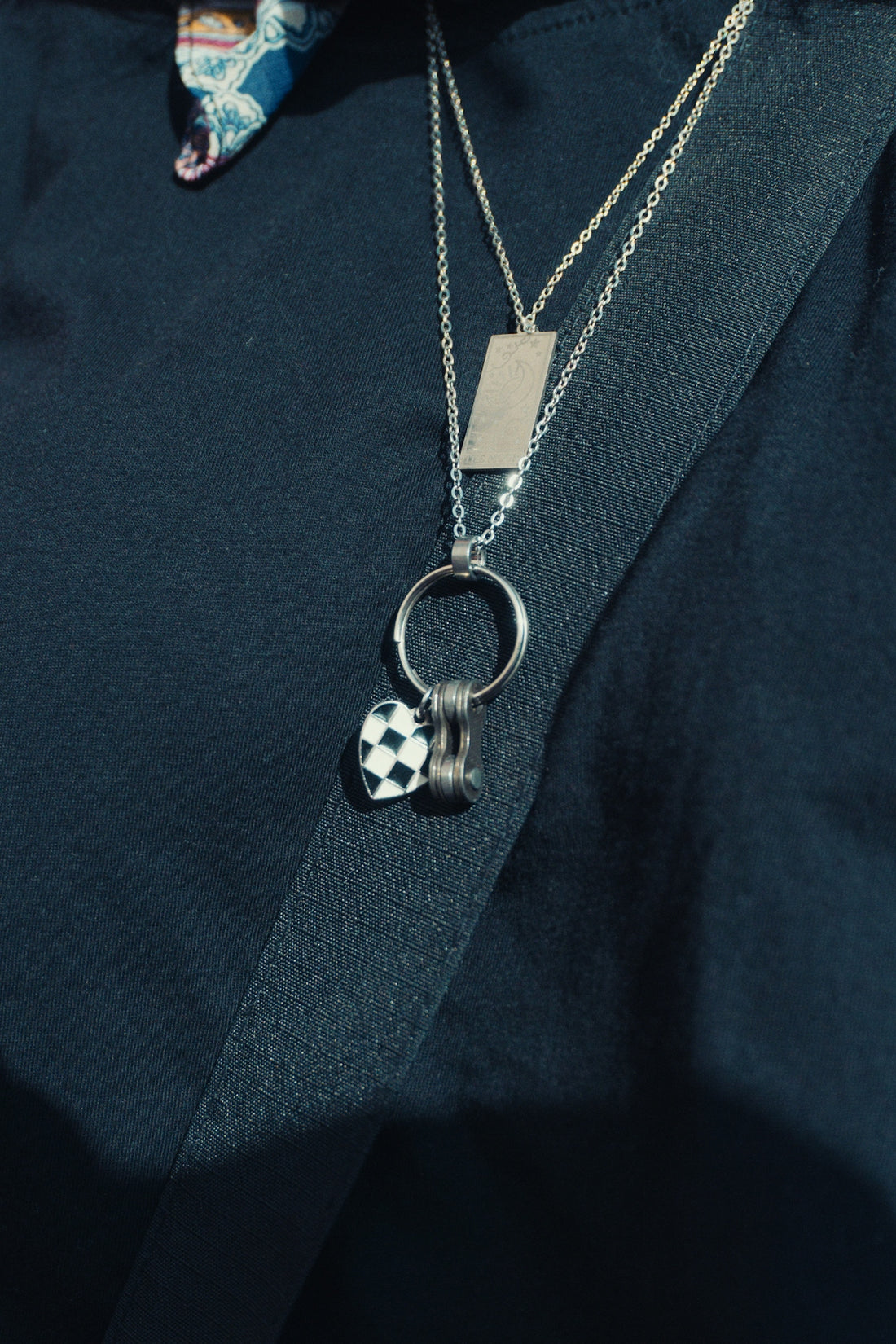 Silver necklaces with soccer ball charm on a dark shirt.