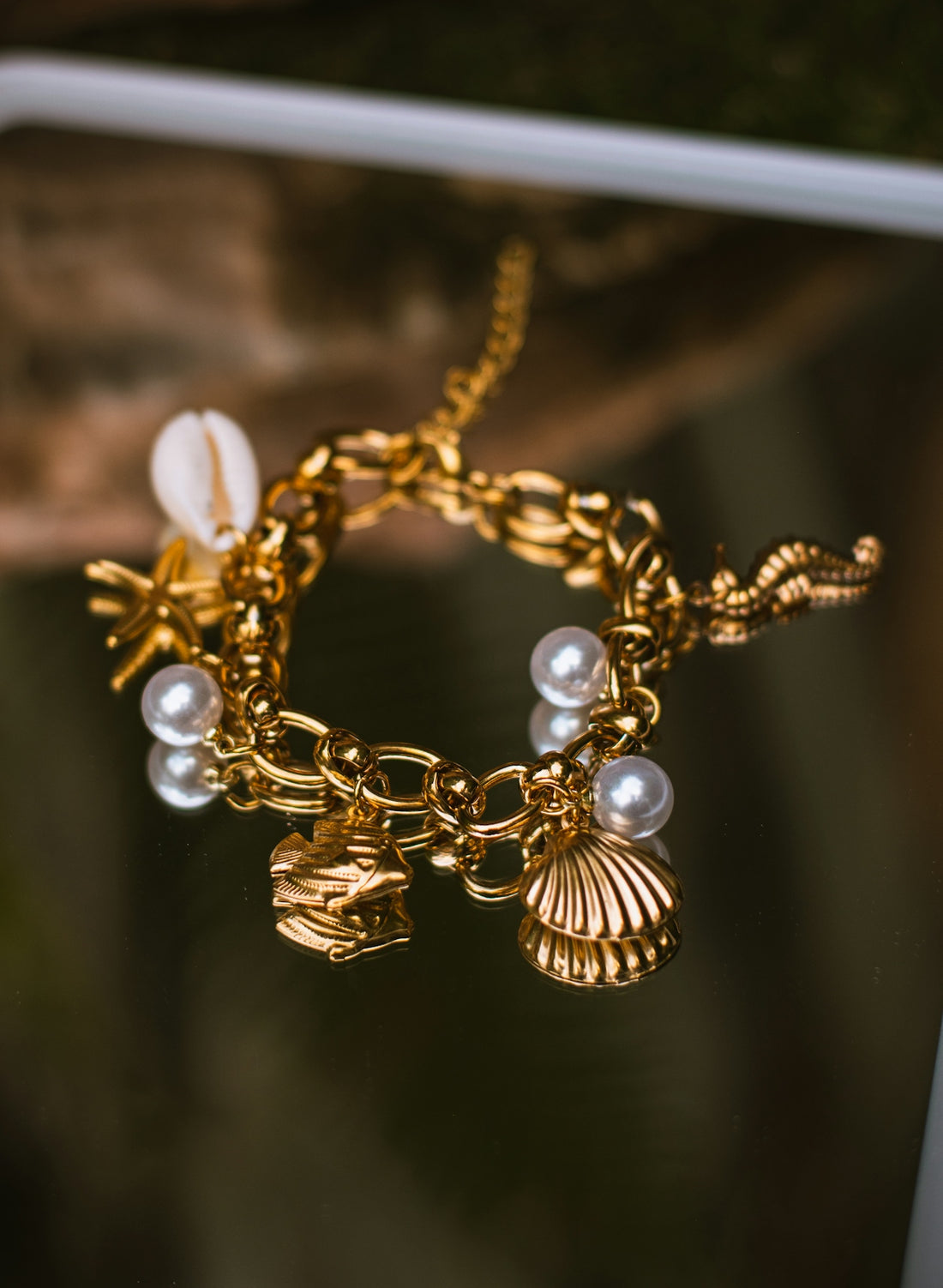 A gold charm bracelet with pearls and shell charms.