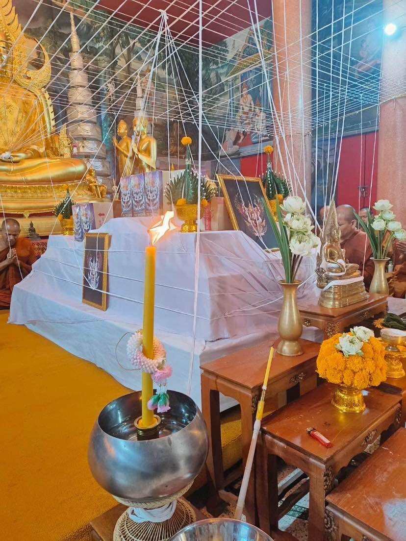 Ceremony setting with authentic Thai guardian amulet on display near a golden Buddha statue