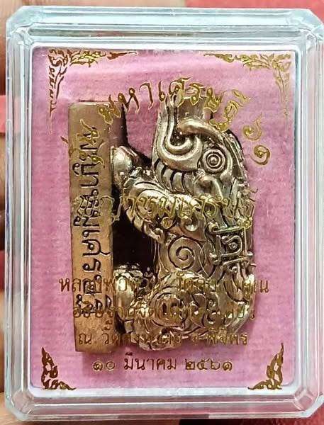 Phaya Moo Setthi Amulet - Luang Por Whan’s. Gold talisman in clear display case on pink velvet with Thai script