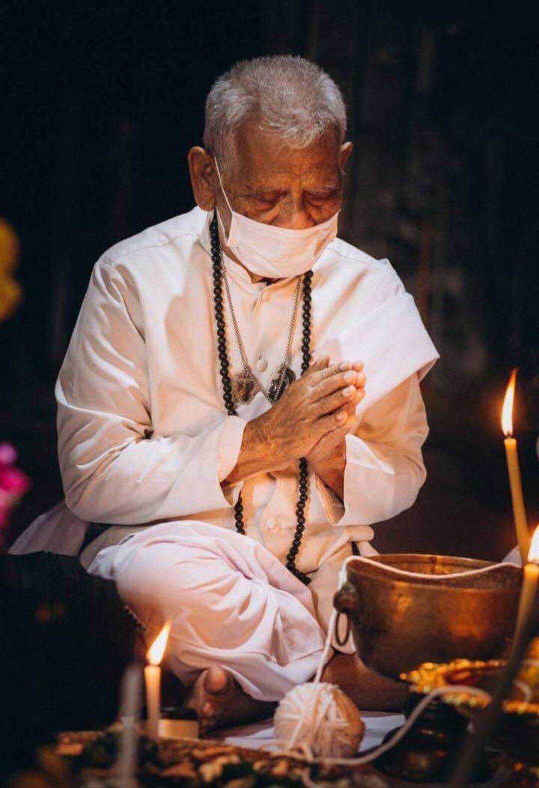 Elderly man praying with Ajan Plean Hatyannont sacred buffalo charm necklace during a spiritual ritual