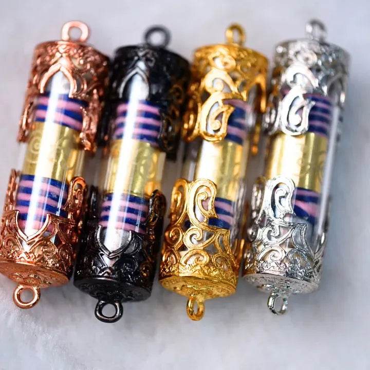 Four ornate cylindrical amulets in rose gold black gold and silver with inner scrolls akrut Maha Prap – Protective Amulet