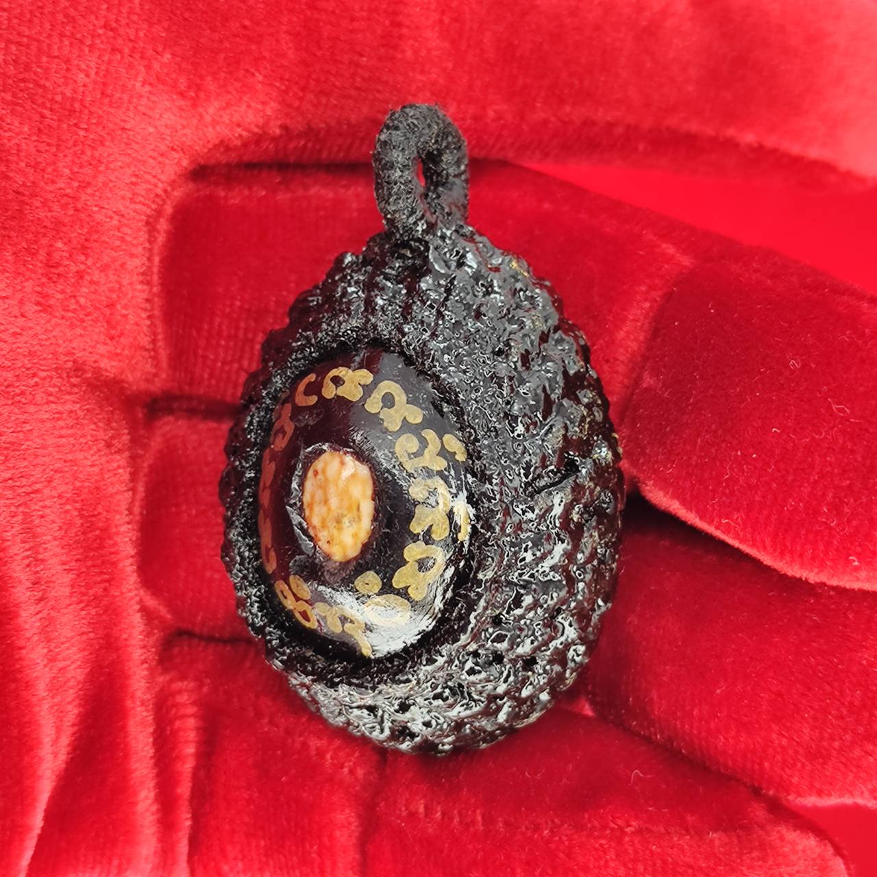 Bia Gae amulet for protection held in a hand, featuring intricate designs and a glossy finish