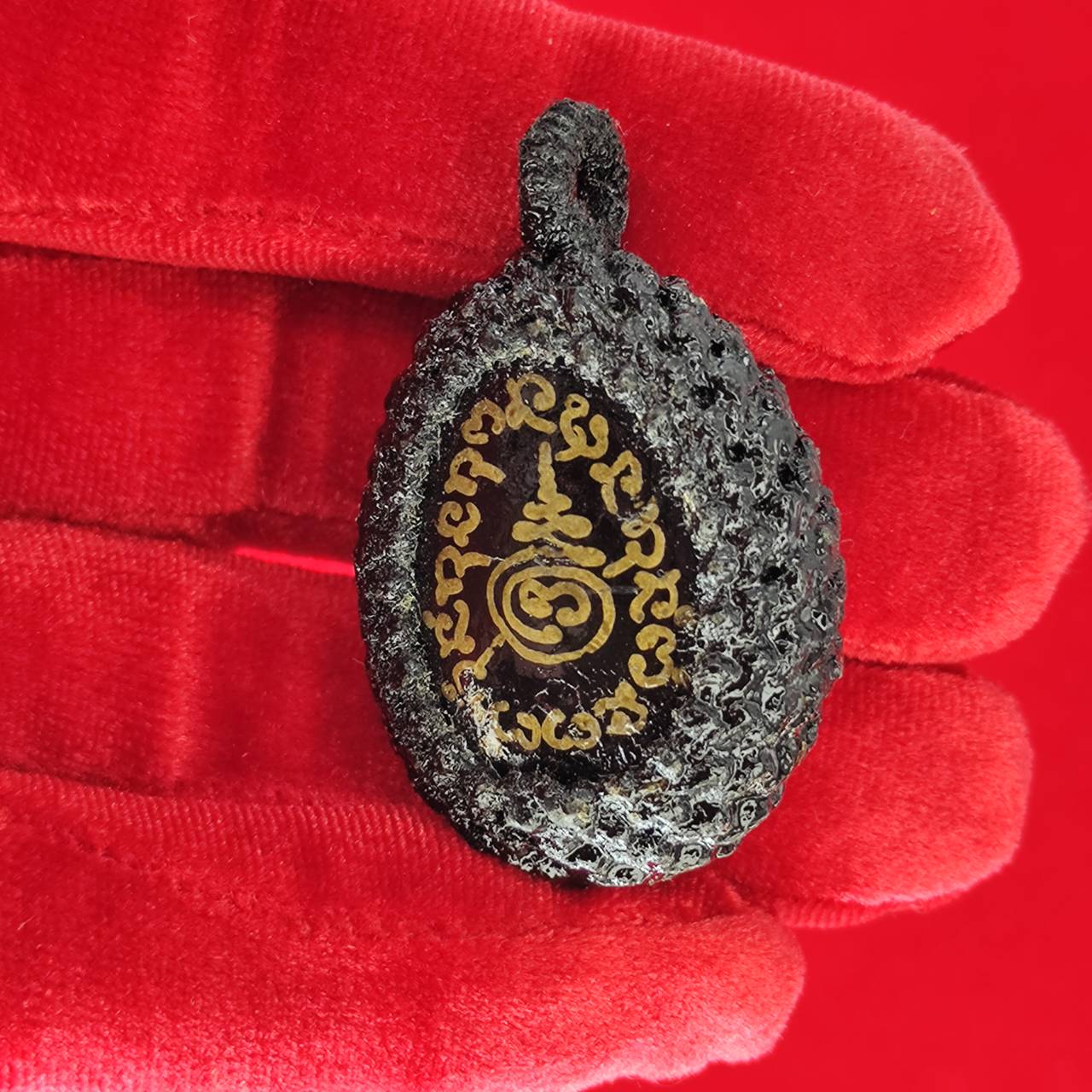 Bia Gae amulet for protection, intricately designed with mystical symbols and held in a gloved hand