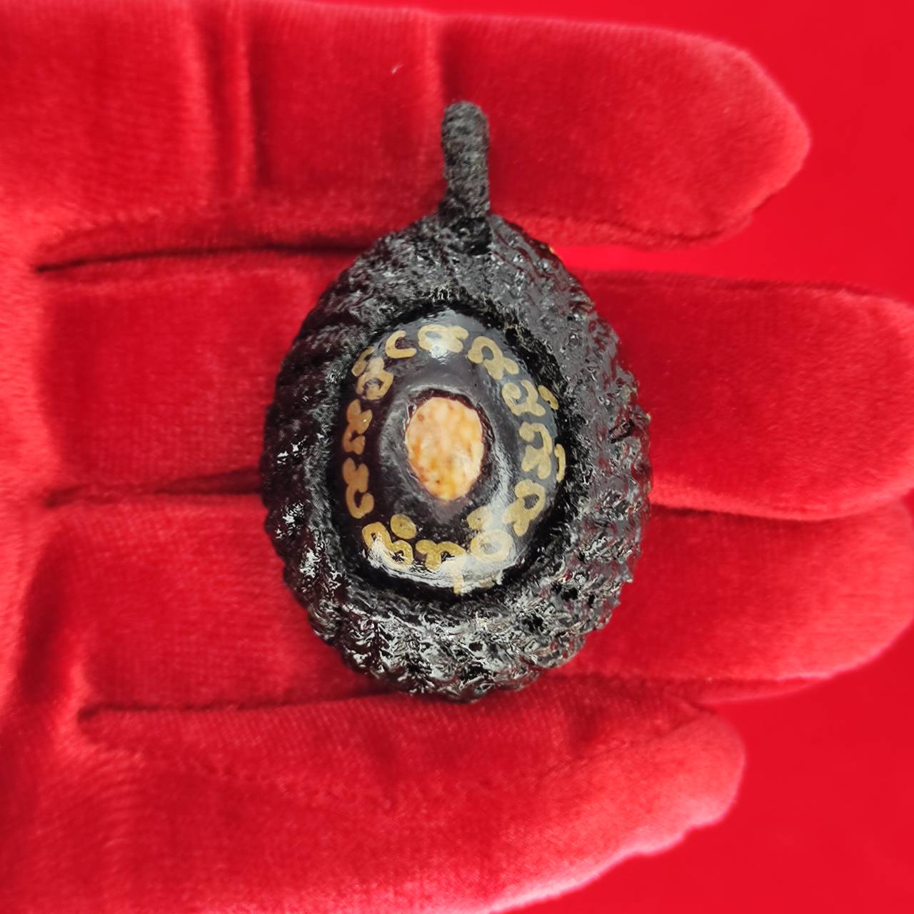 Bia Gae amulet for protection shown in hand, featuring intricate designs and detailed craftsmanship