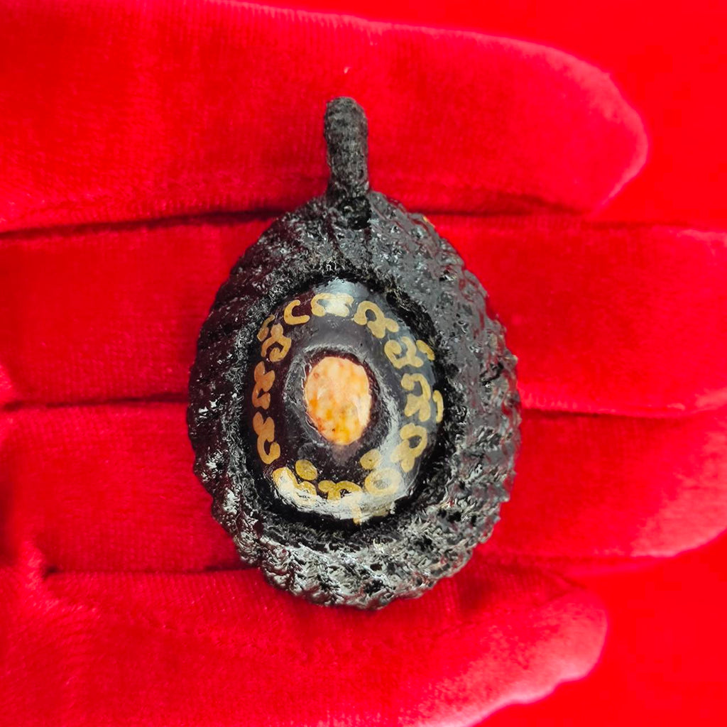 Bia Gae amulet for protection displayed on red fabric with intricate details and vivid colors