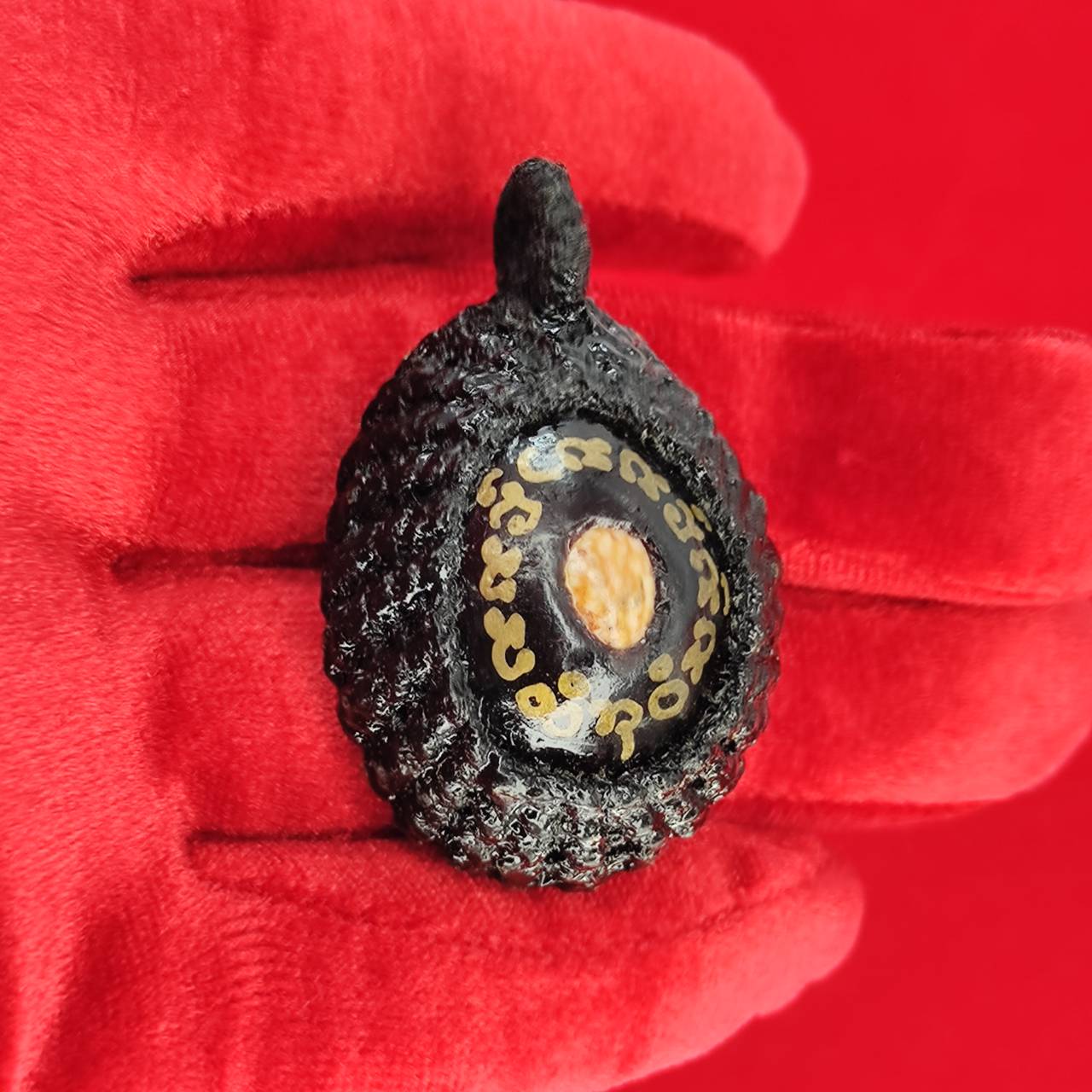 Bia Gae amulet for protection displayed in hand with detailed design and texture