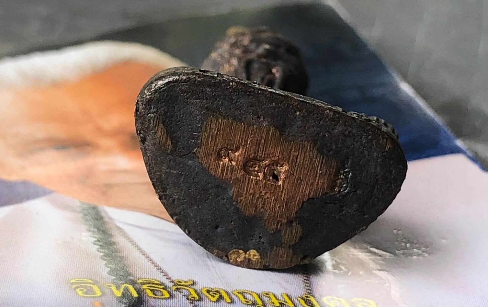 Borom Kru Phra Ruesi Ta Fai Amulet triangular dark metal base with copper inlay and stamped marks on magazine