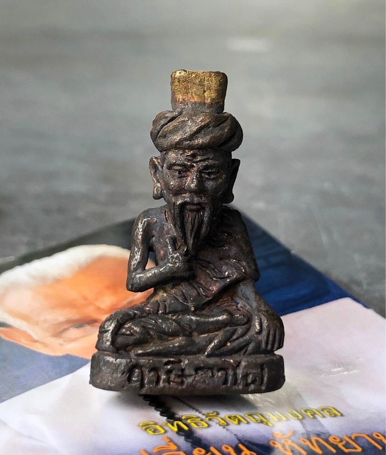Bronze seated hermit amulet with turban and beard on engraved base Borom Kru Phra Ruesi Ta Fai Amulet .