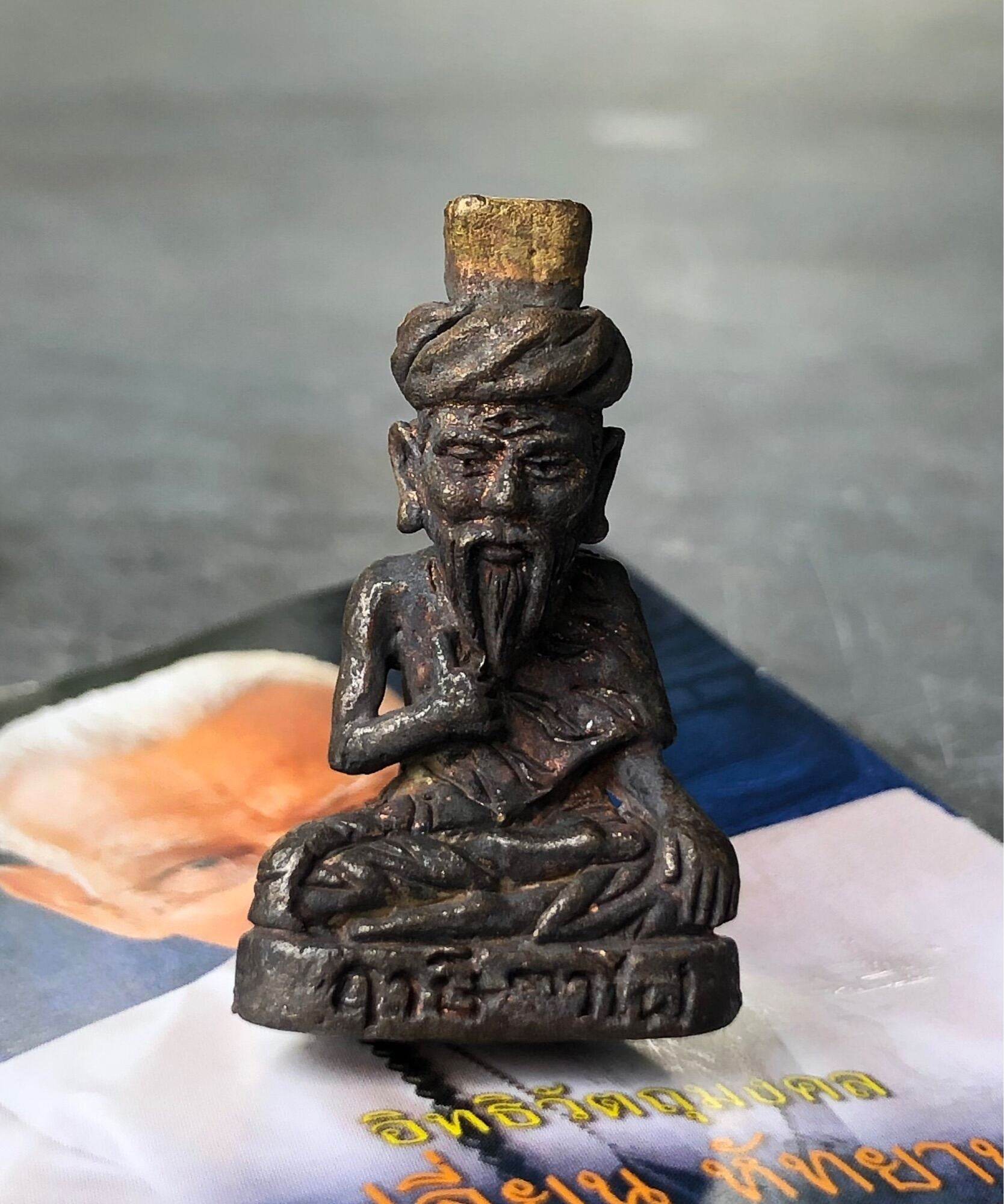 Antique bronze seated sage amulet on paper with Thai text Borom Kru Phra Ruesi Ta Fai Amulet . Rustic patina and turbaned figure