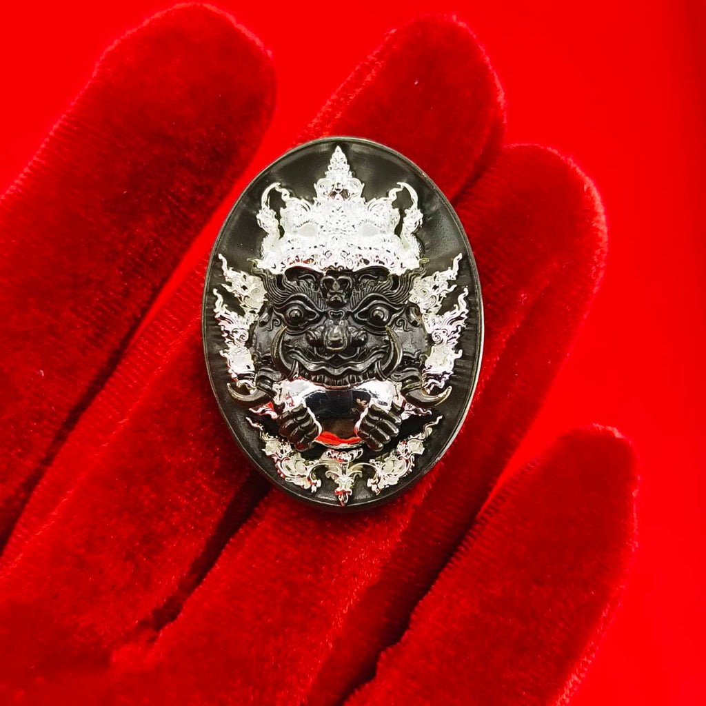 Rahu amulet coin for prosperity displayed on a red velvet background with intricate designs