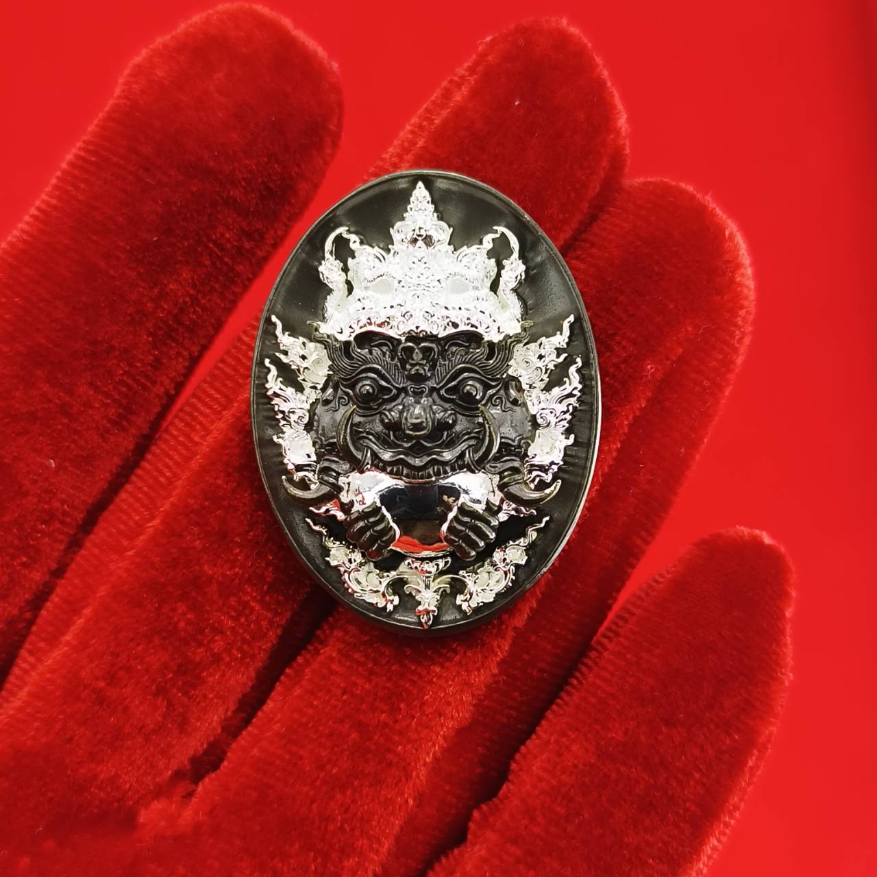 Rahu amulet coin for prosperity displayed on a red velvet background with intricate designs