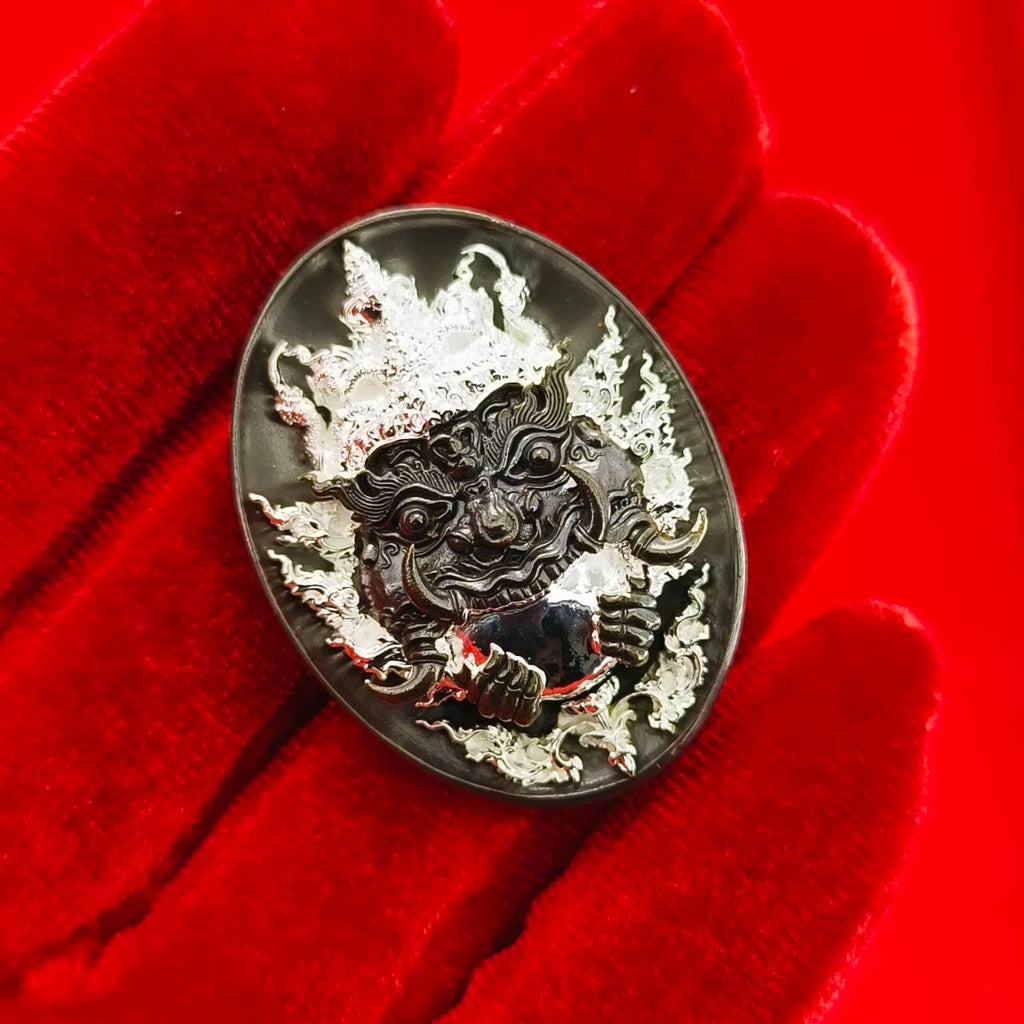 Rahu amulet coin for prosperity in a detailed design, held on a red velvet background
