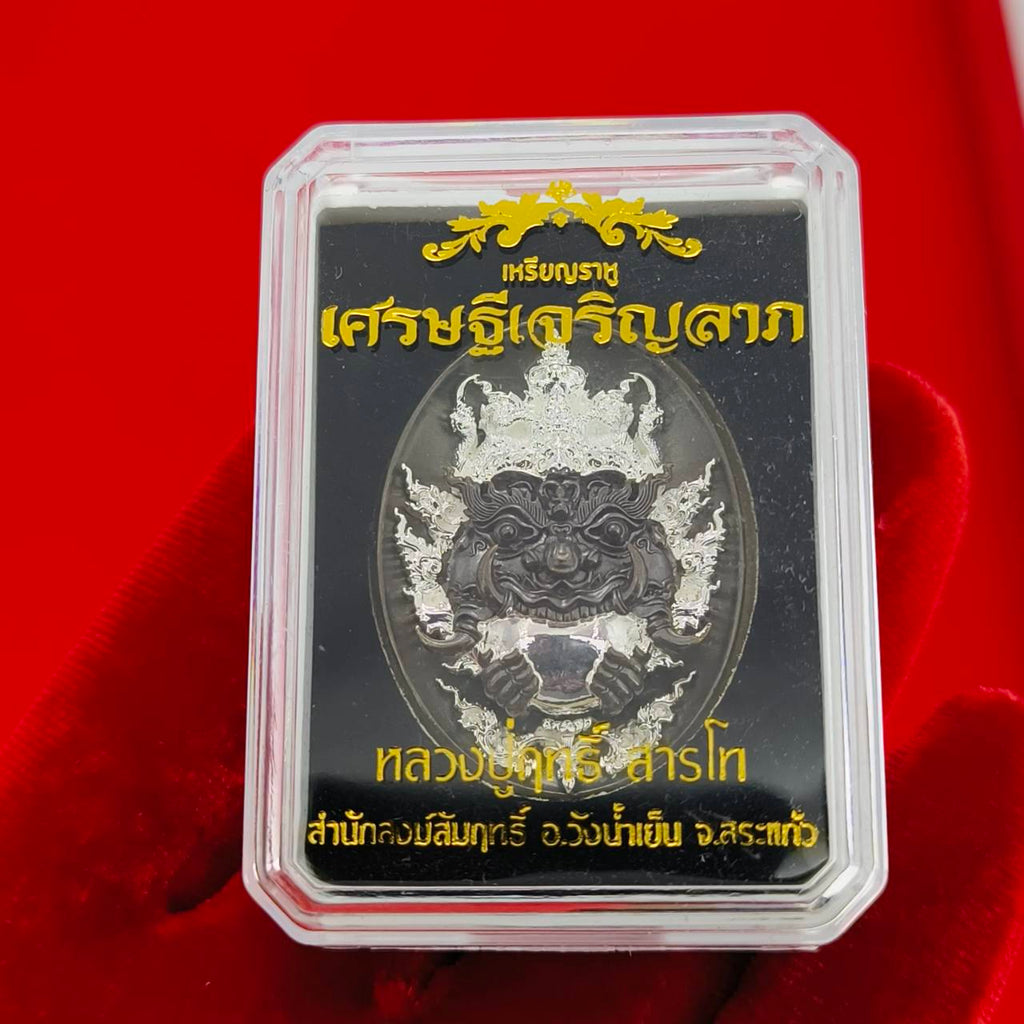 Rahu amulet coin for prosperity encased in a protective plastic with intricate design