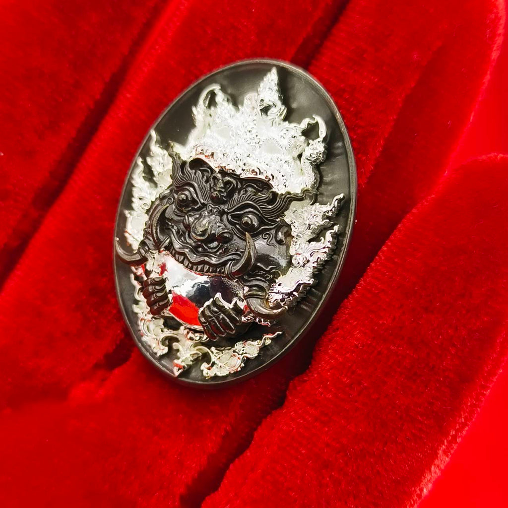 Rahu amulet coin for prosperity displayed on red velvet, featuring intricate design of Rahu