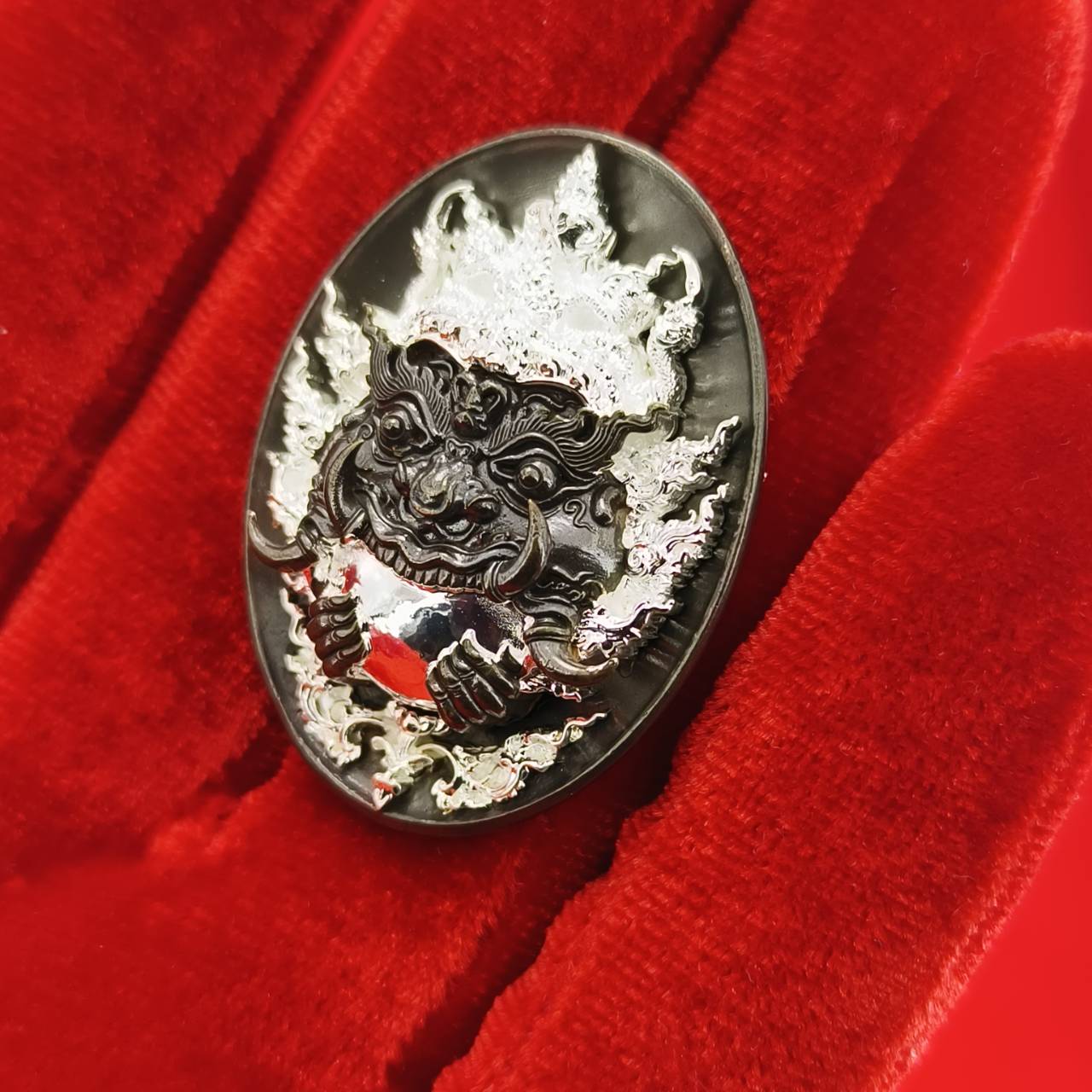 Rahu amulet coin for prosperity displayed on red velvet, featuring intricate design of Rahu