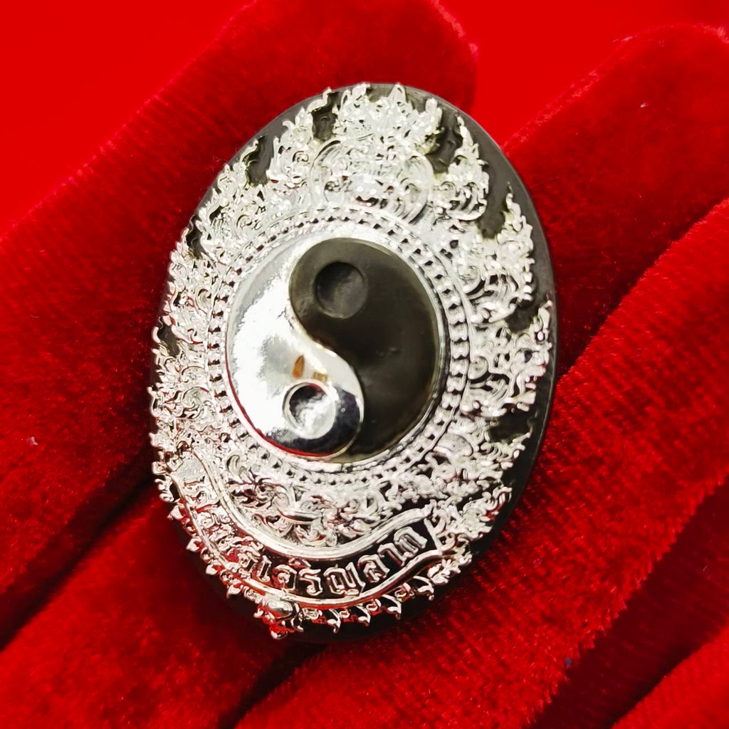 Rahu amulet coin for prosperity with intricate designs in black and silver, held on a red cloth