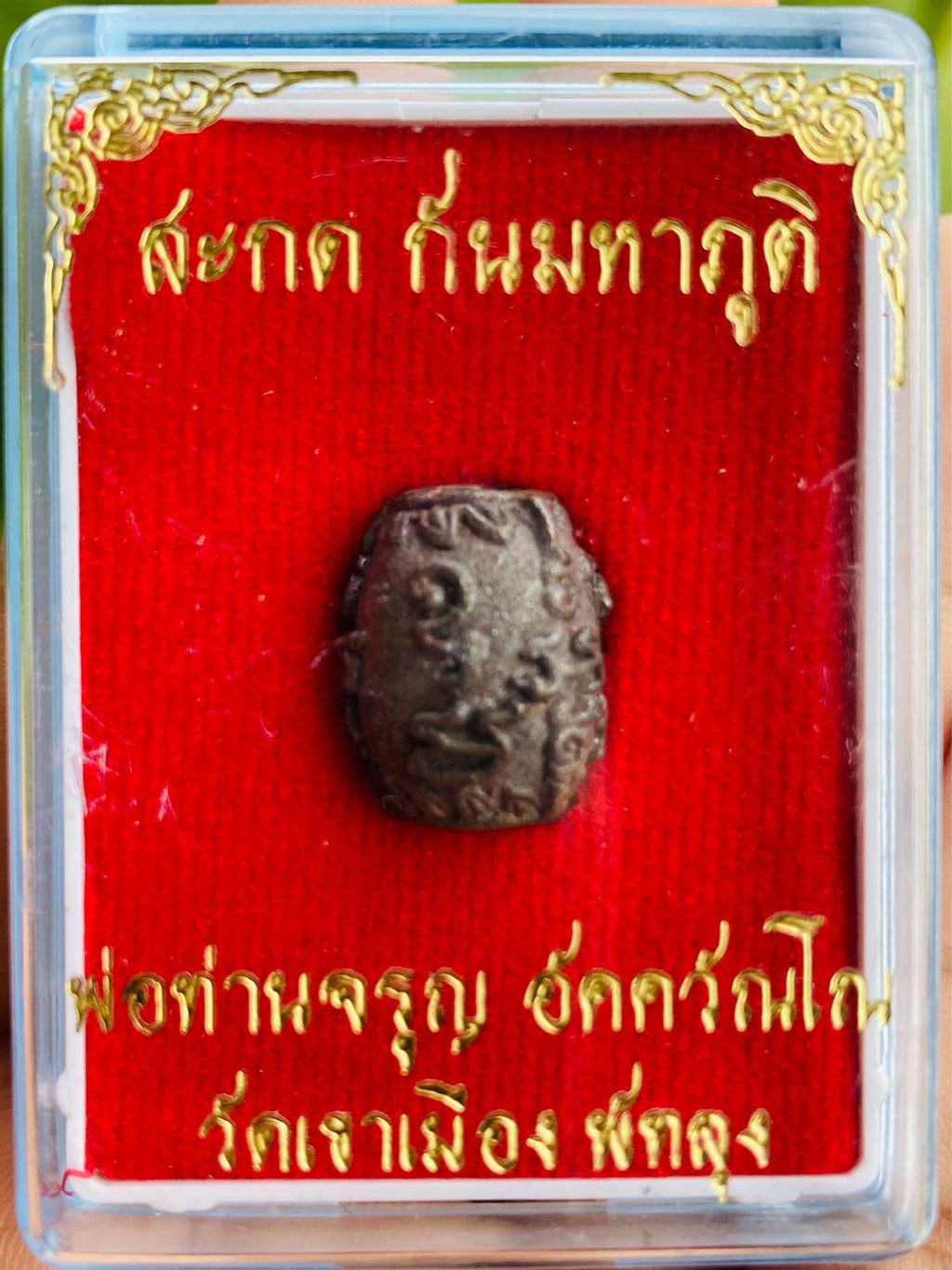 Thai Blessing Co Thai amulet in clear display box on red velvet with gold script negative energy protection charm