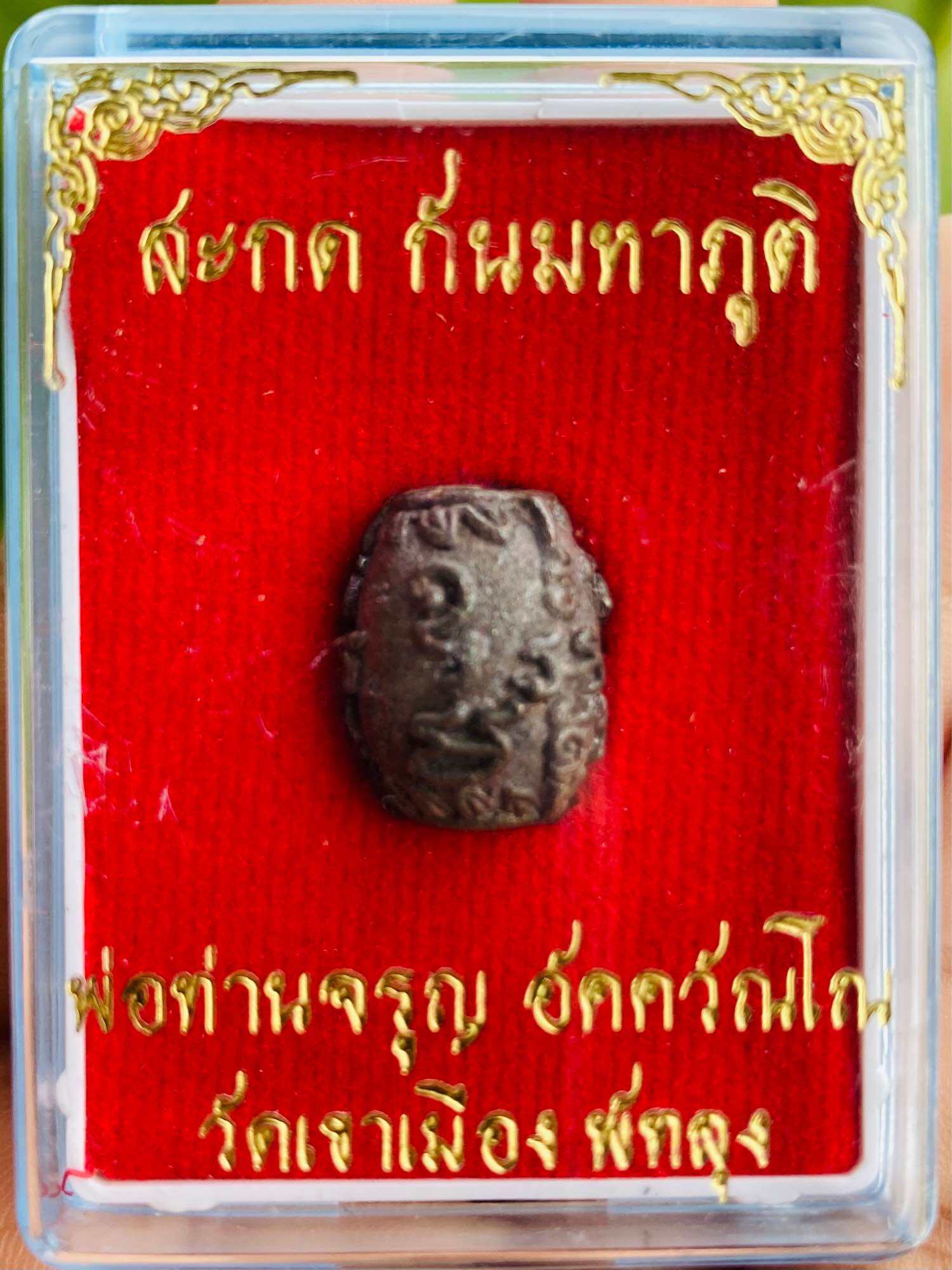 Thai Blessing Co Thai amulet in clear display box on red velvet with gold script negative energy protection charm
