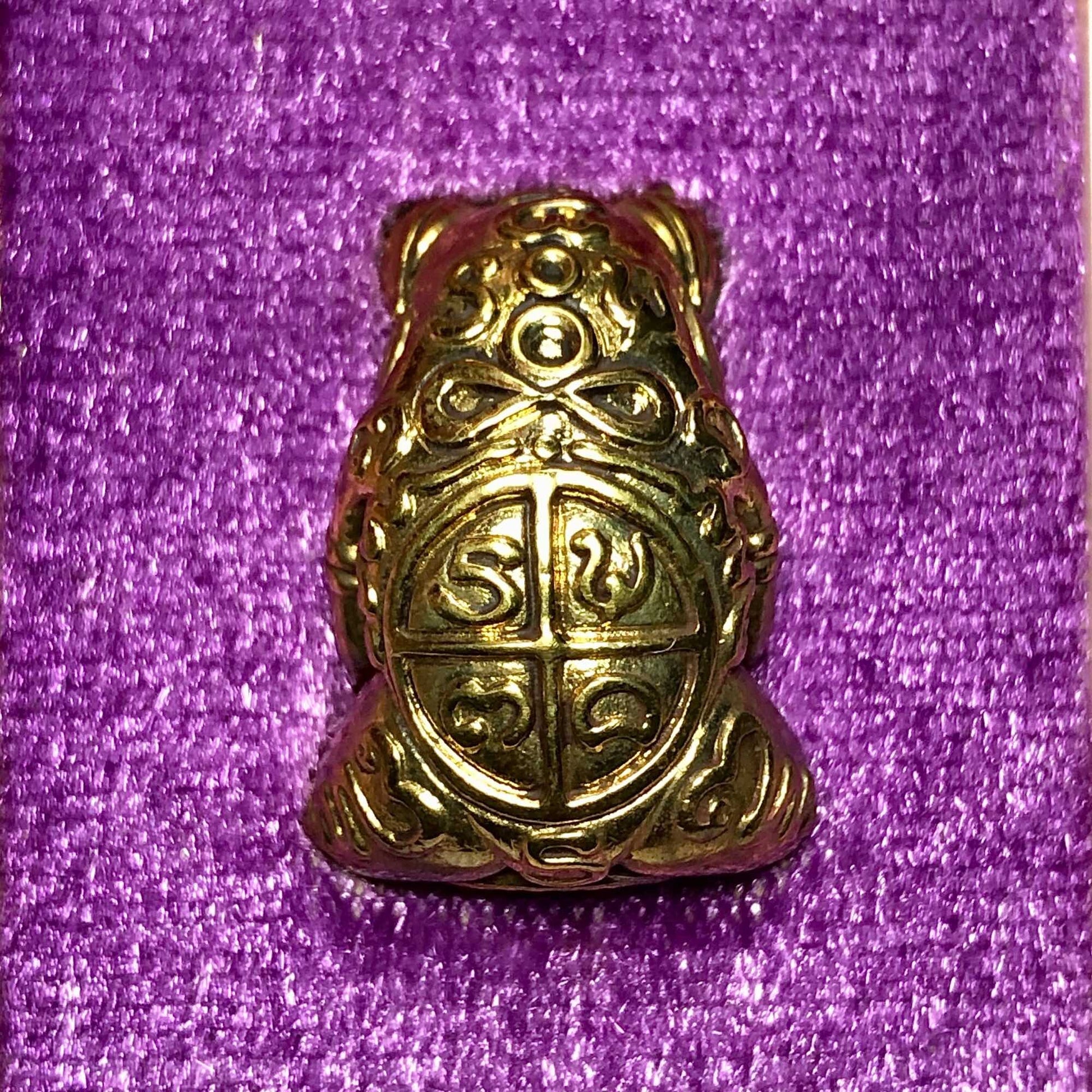 Thai Blessing Co gold frog amulet pendant Phaya Kob Kin Duean . ornate engraved talisman on purple fabric