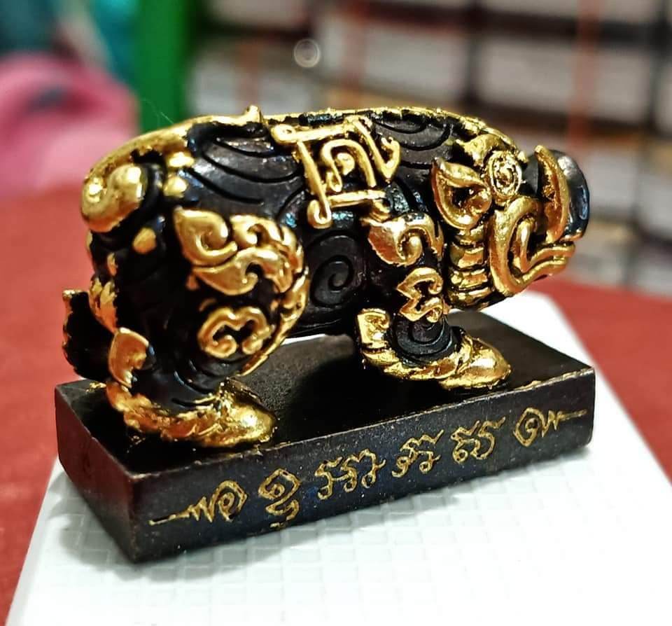 Phaya Moo Setthi black and gold pig talisman statue on base with Thai script feng shui prosperity decor