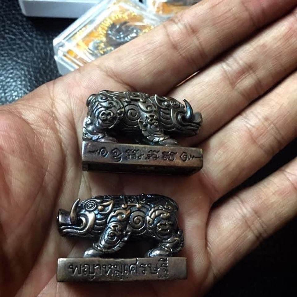 Phaya Moo Setthi small bronze rhino amulet set with engraved bases held in palm Feng Shui talisman