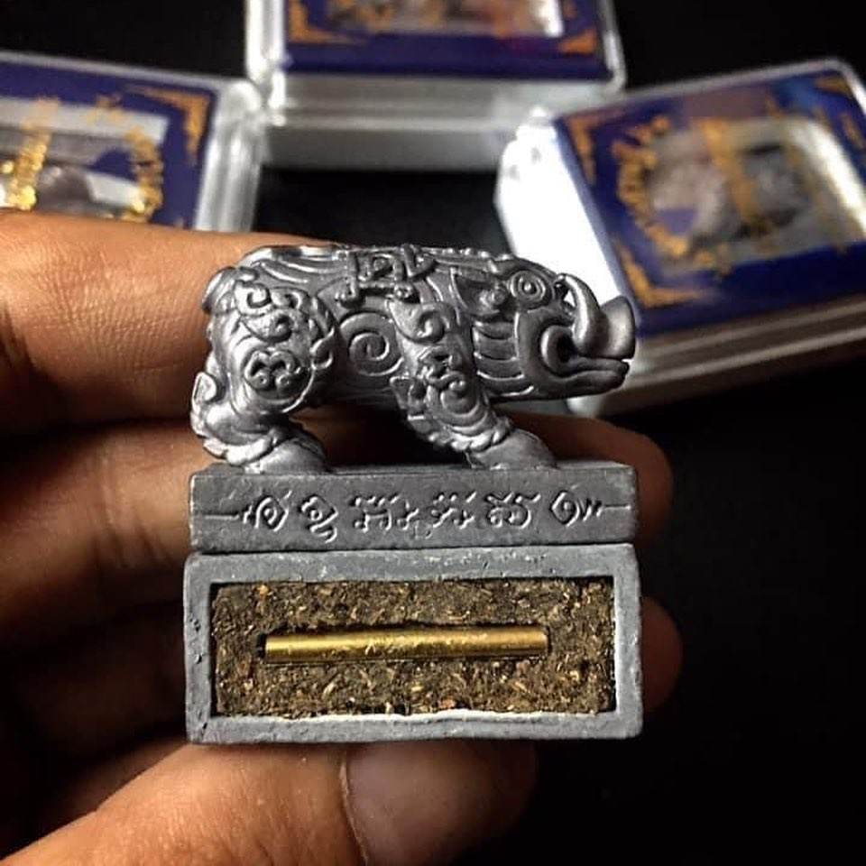 Phaya Moo Setthi Thai talisman silver pig amulet on engraved base with gold relic tube held in hand