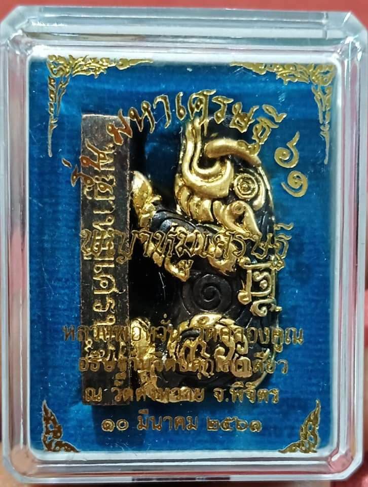 Phaya Moo Setthi gold amulet in clear display case on blue velvet background for luck and prosperity