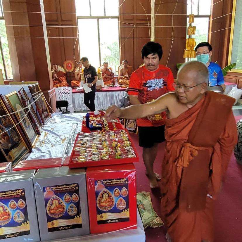 Phra Pidta amulet for prosperity displayed at a religious event with a monk selecting items