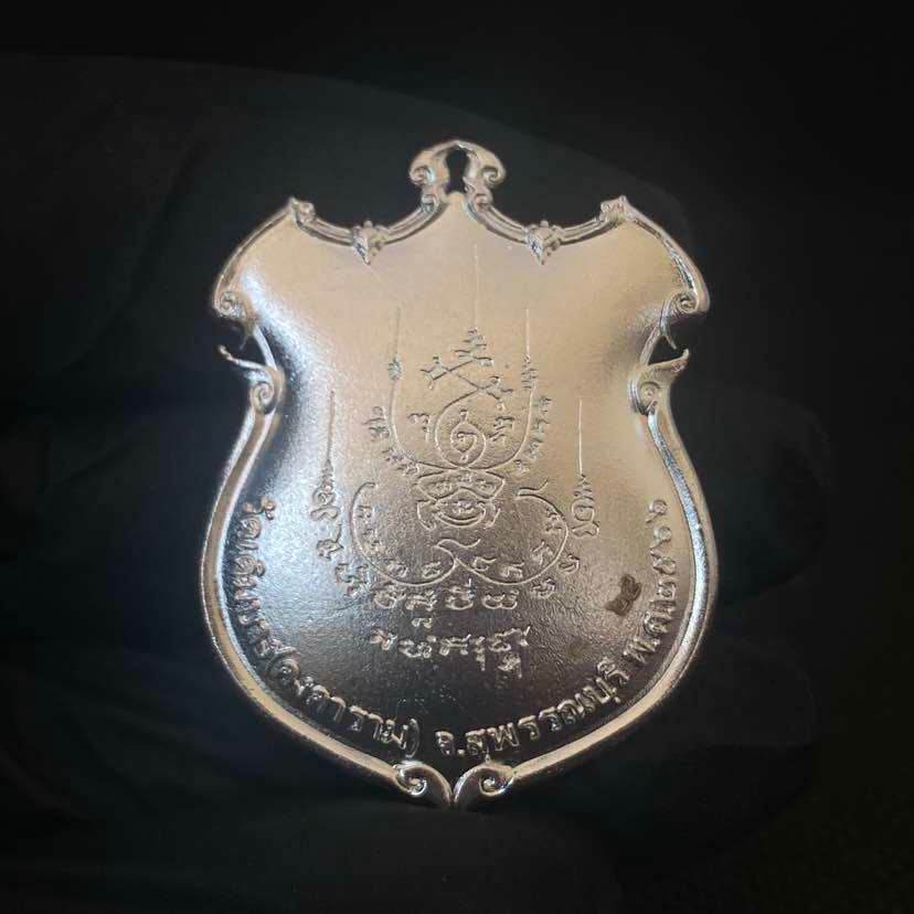 Silver shield amulet plaque engraved with yantra and Thai script on black background Thao Wessuwanno Sodaprom .