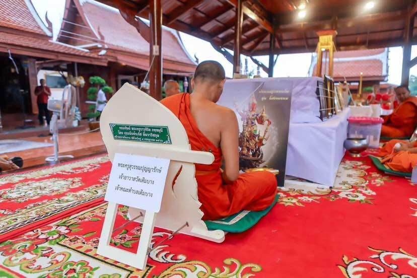 Thao Wessuwanno Sodaprom amulet blessing ceremony with Buddhist monk in orange robes seated on ornate temple carpet