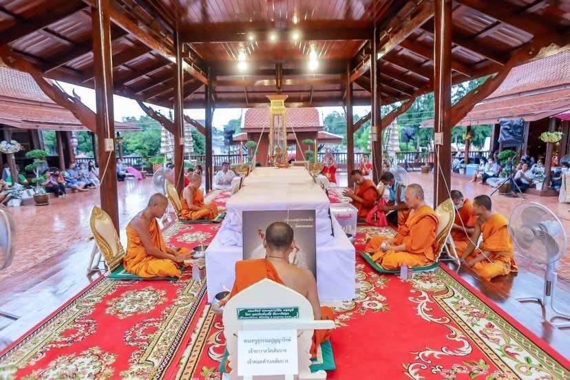 Thao Wessuwanno Sodaprom amulet during a temple blessing ceremony with orange robed monks seated around a white casket