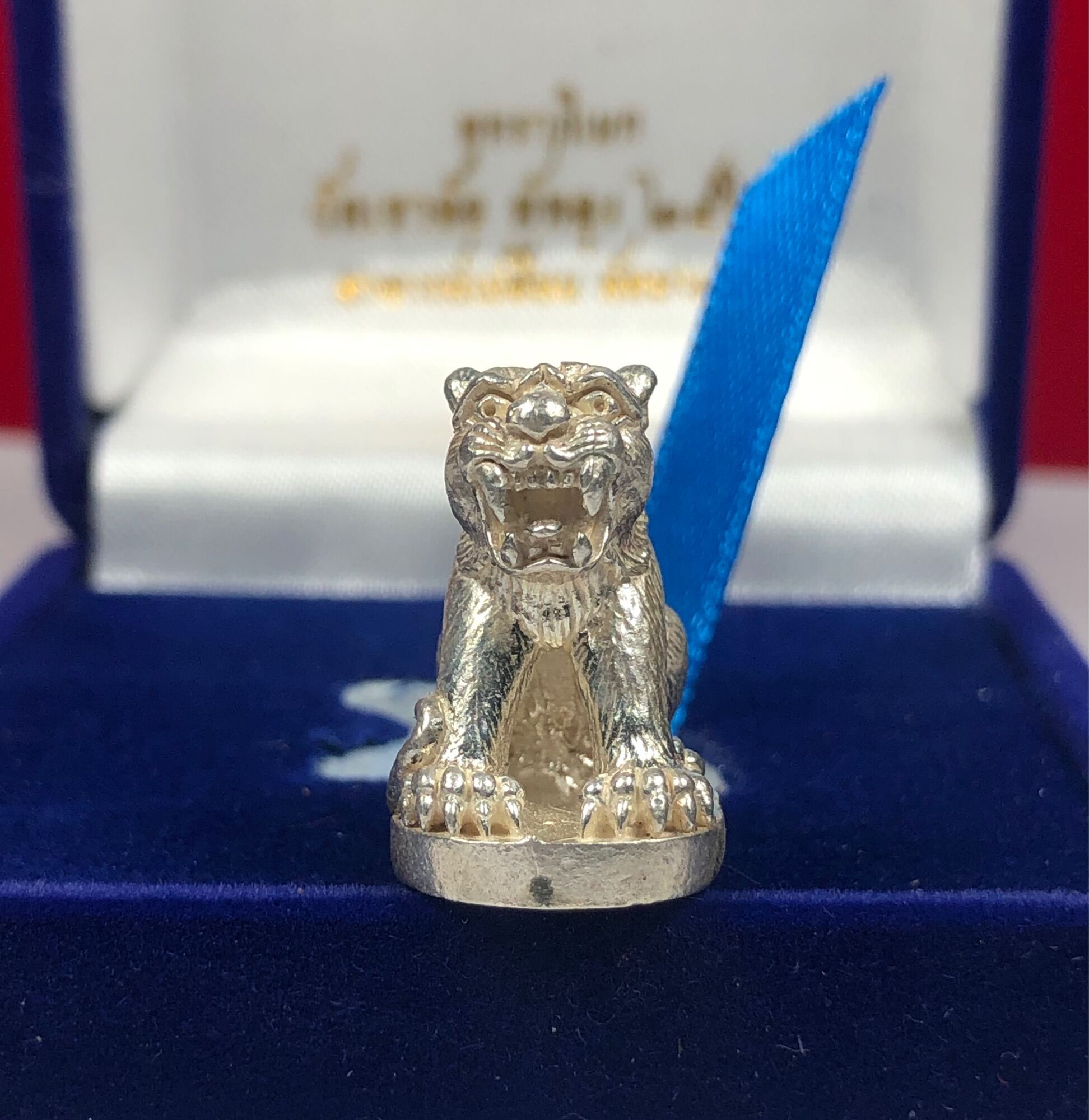 Silver tiger amulet for protection displayed in a blue velvet box with a blue ribbon