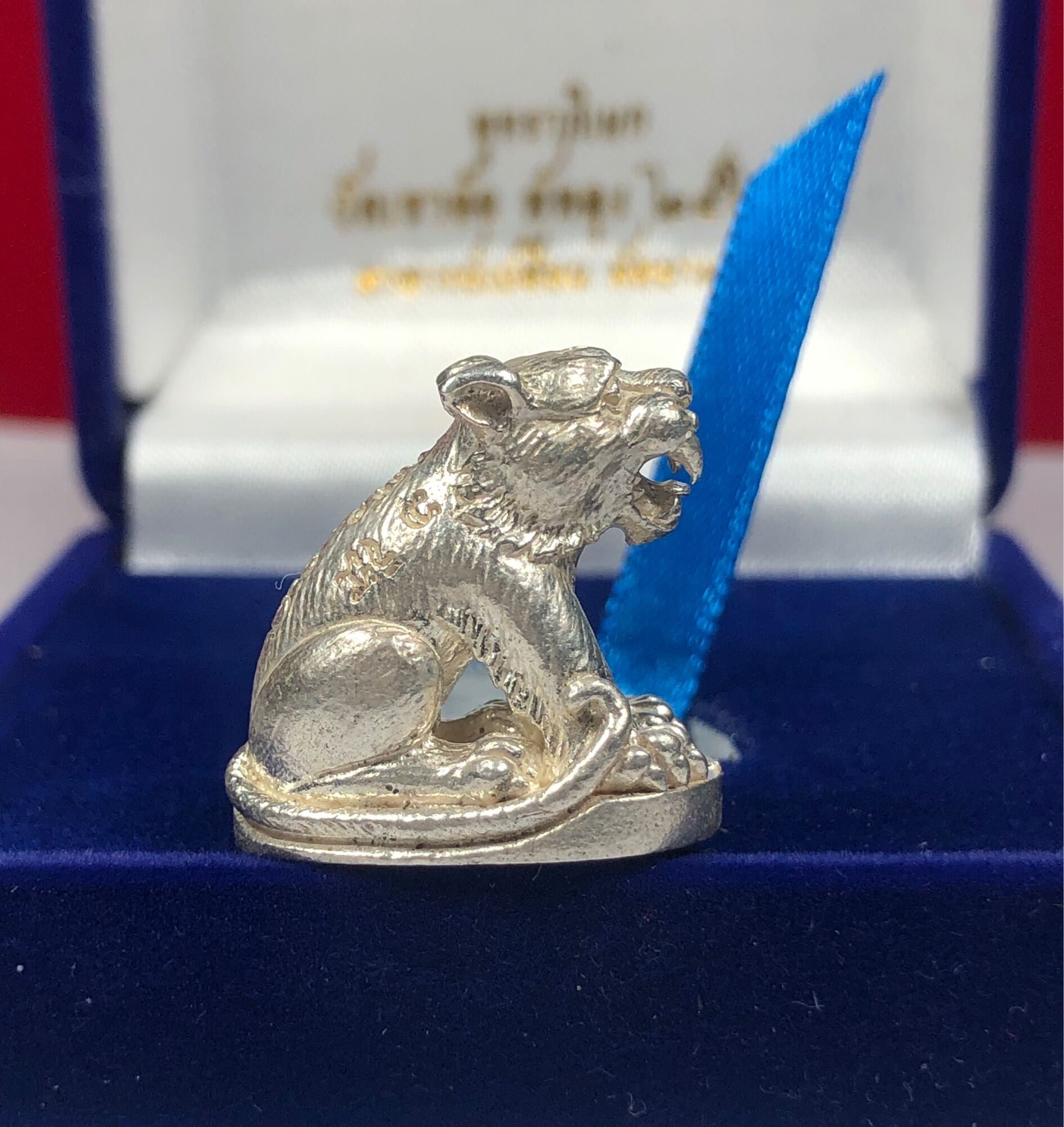 Silver tiger amulet for protection detailed in a blue velvet box with a blue ribbon