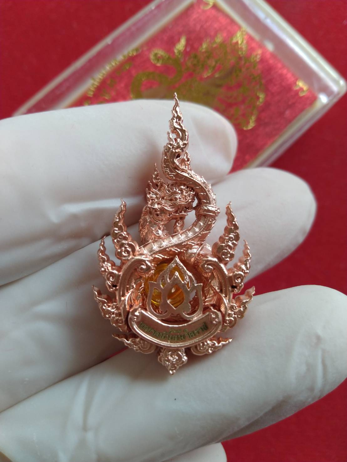 Anantanakarach Naga amulet pendant rose gold metal ornate Thai Naga pendant held in gloved hand