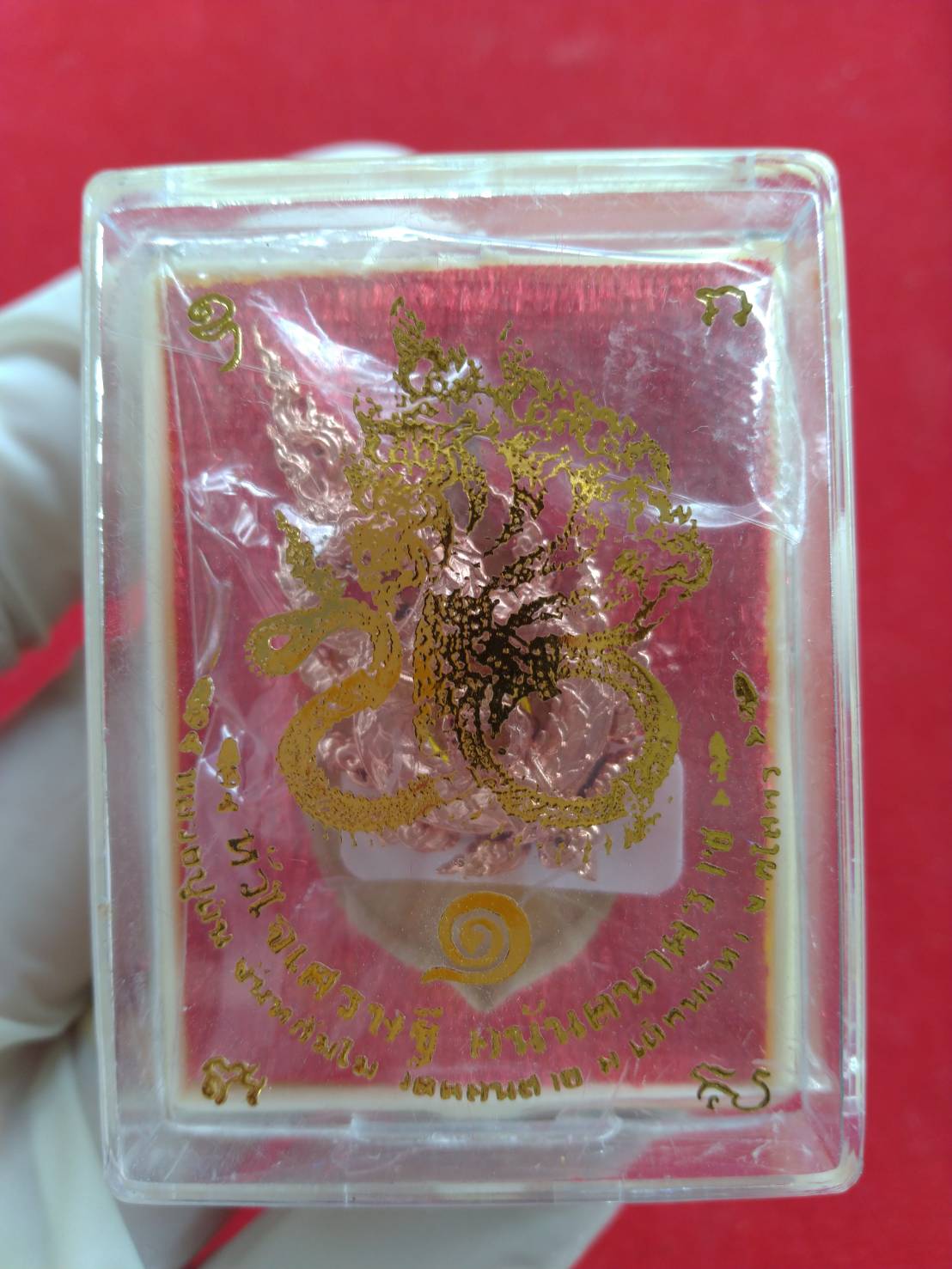 Anantanakarach Naga amulet pendant in clear plastic display case with gold Naga design and Thai script
