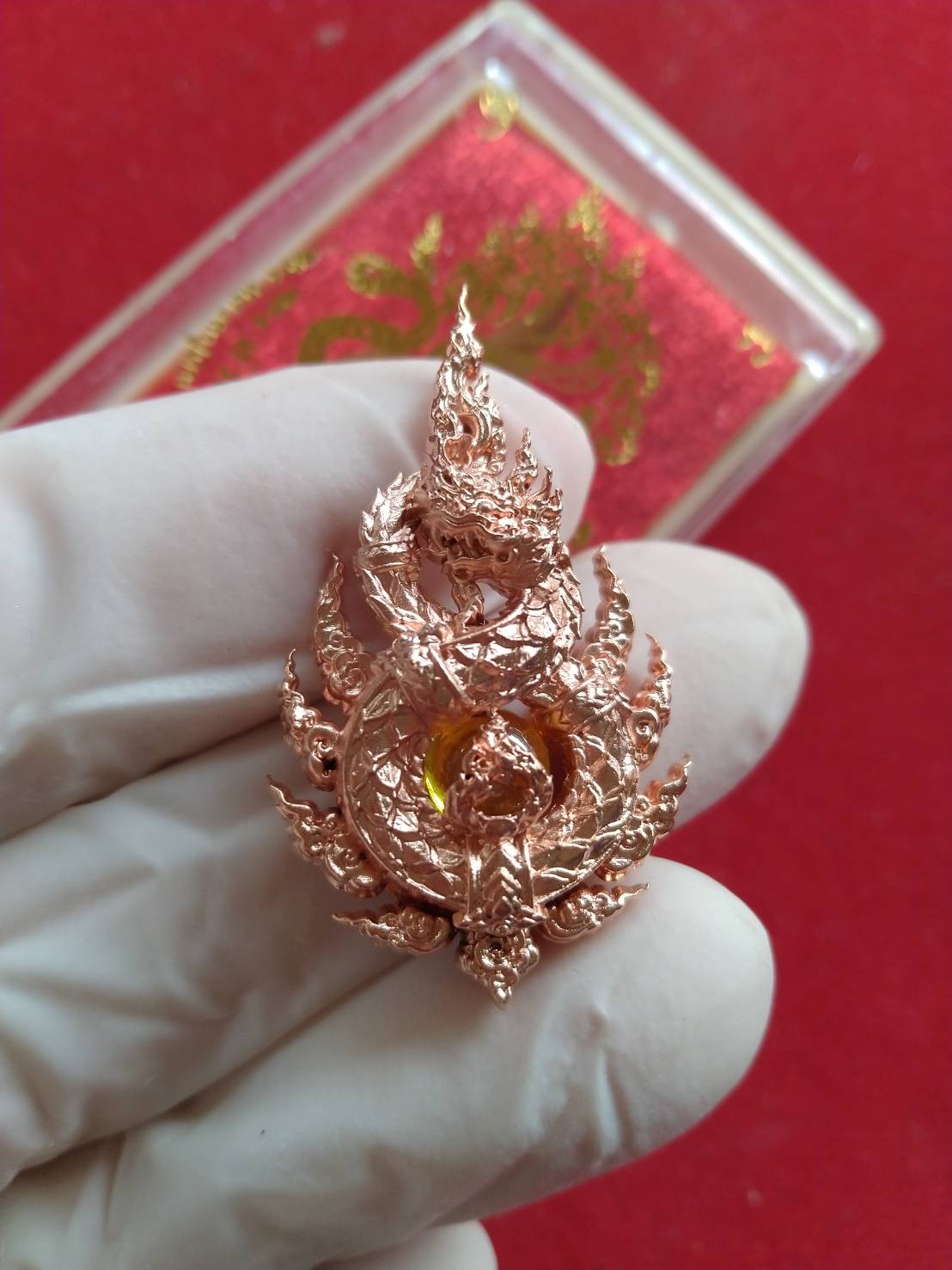 Anantanakarach Naga amulet pendant rose gold ornate Thai blessing piece with central amber gem held in gloved hand