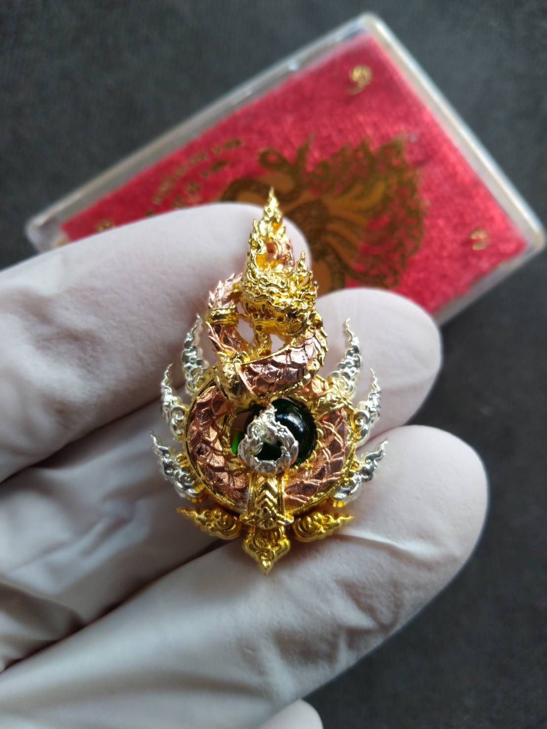 Anantanakharaj pendant Thailand ornate gold and rose gold Naga amulet in a gloved hand from Thai Blessing Co