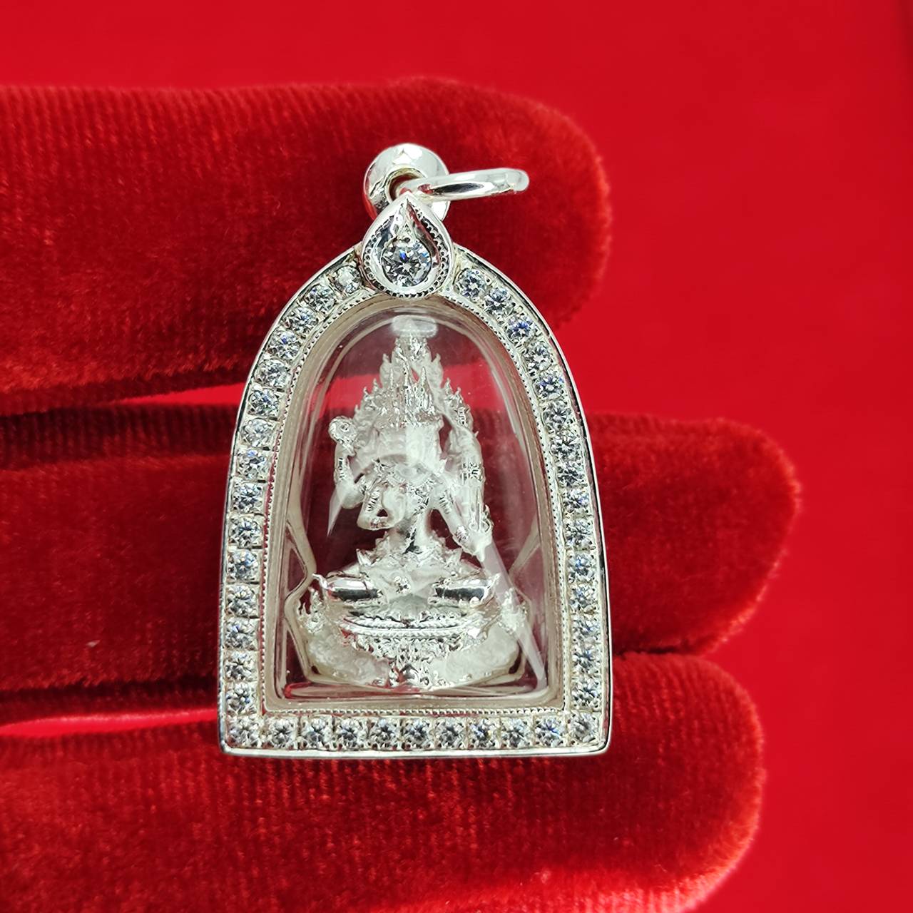 Brahma Naga amulet with silver frame. Pendant in clear case with rhinestones on red velvet background