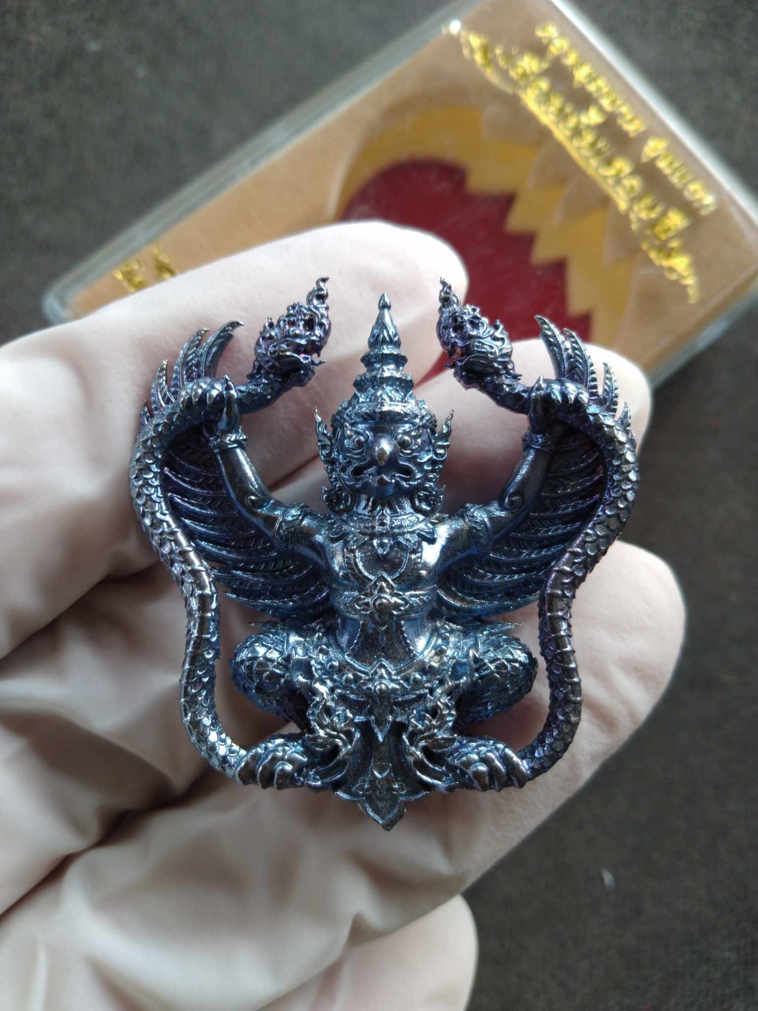 Handheld detailed metal Garuda amulet blessed by Luang Pho Sanan. Intricate Thai sacred pendant