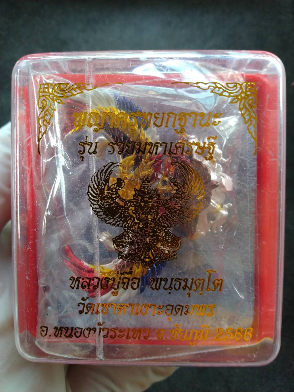 Garuda Phaya Krut Yok Tana Amulet in clear plastic box with red cord and gold Garuda design pendant