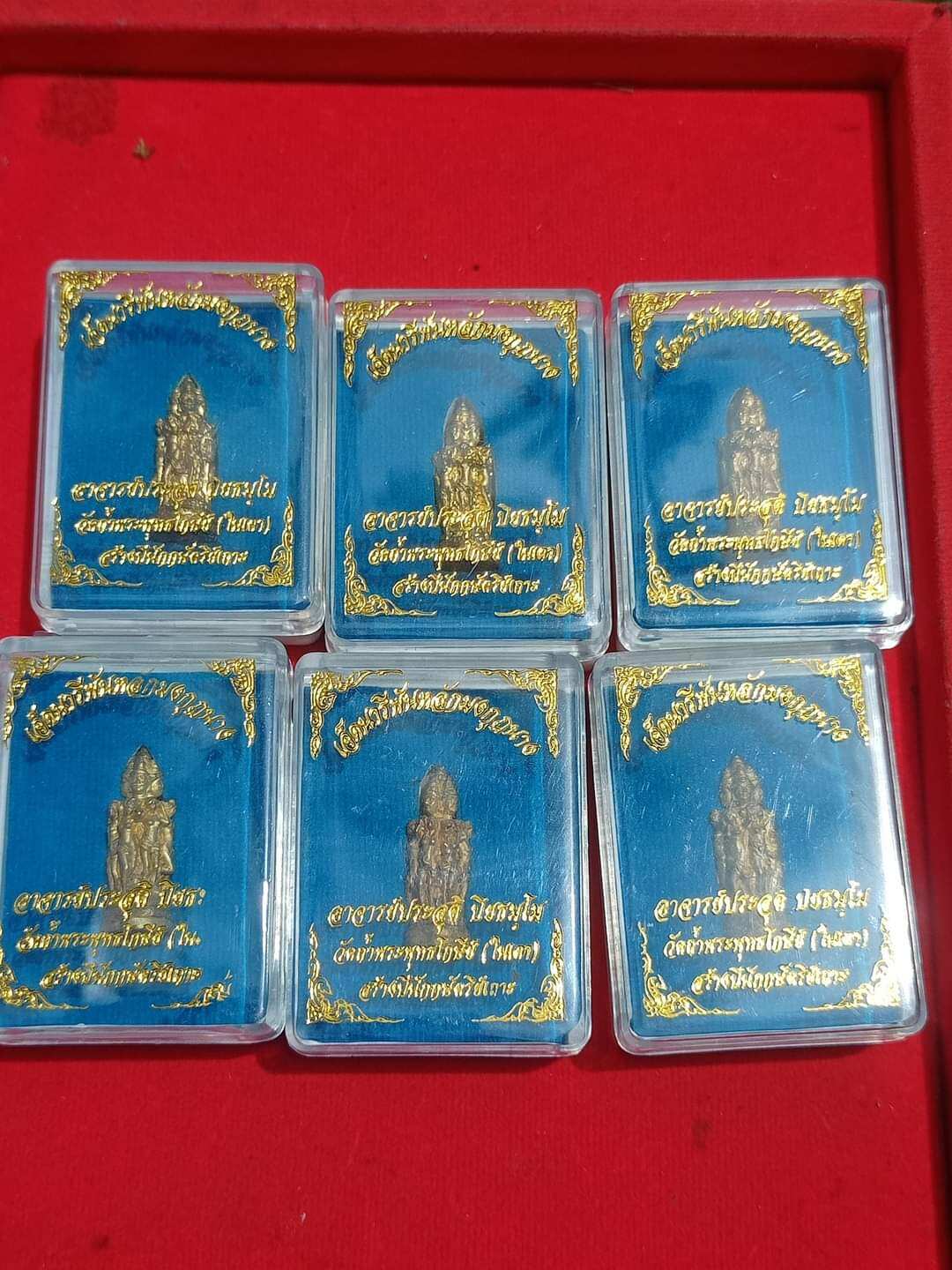 Six Jeed Naree Phan Lak amulet gold pendants in clear cases on blue velvet inside red display box