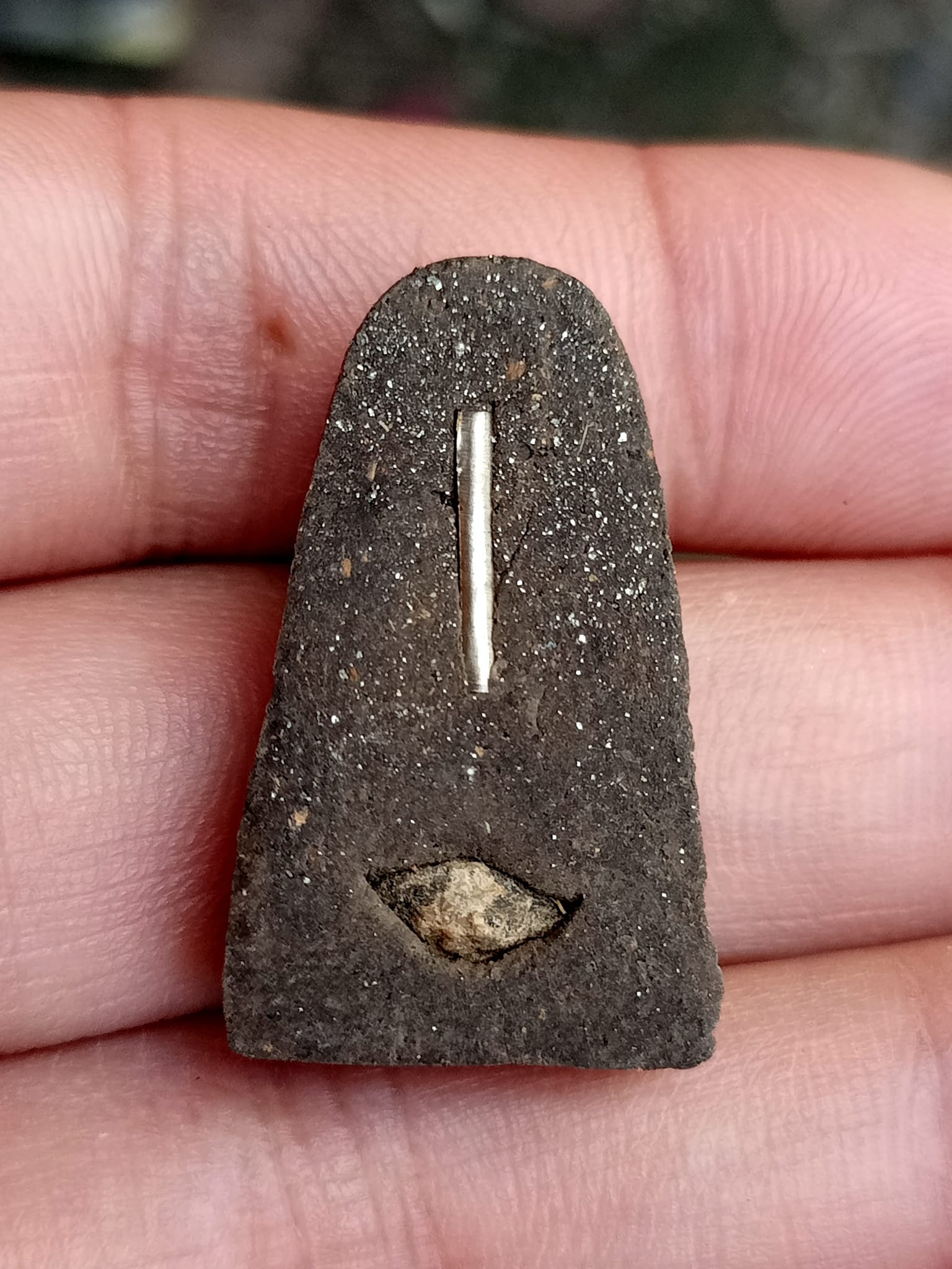 Hand holding small dark Luang Pu Thuad commemorative amulet 2023 with metal insert and relic piece