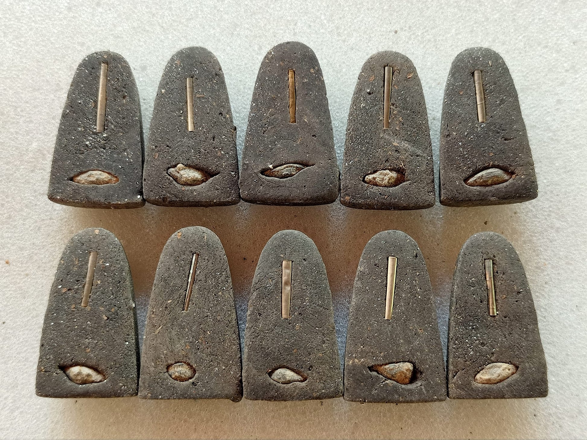 Set of 11 dark triangular Thai amulet pendants with embedded metal pin and shell relic Luang Pu Thuad commemorative amulet 2023