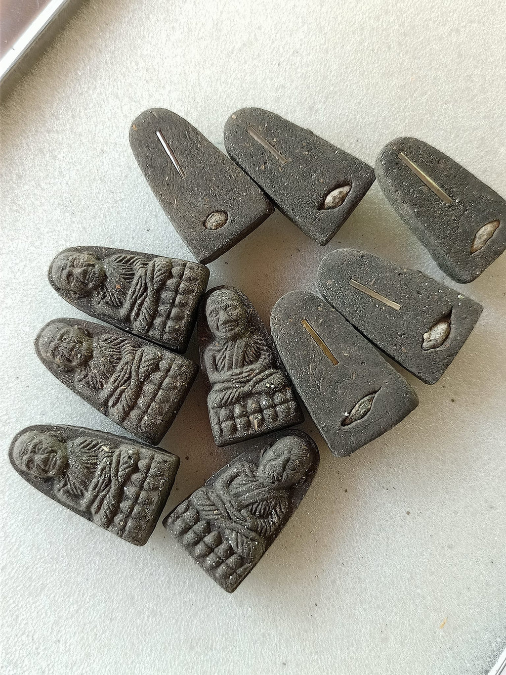 Multiple dark gray Luang Pu Thuad commemorative amulet 2023 pendants showing monk relief fronts and metal inset backs