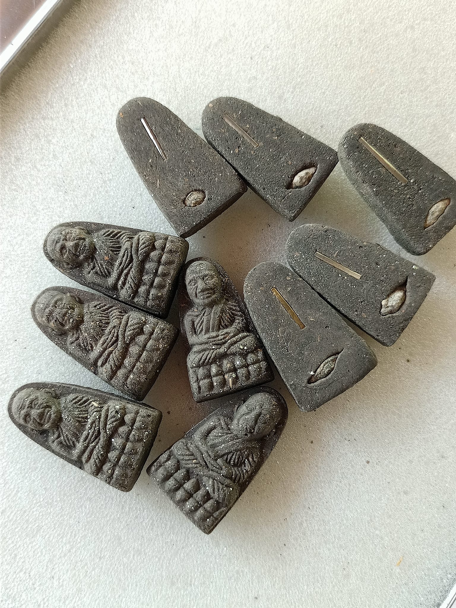 Multiple dark gray Luang Pu Thuad commemorative amulet 2023 pendants showing monk relief fronts and metal inset backs